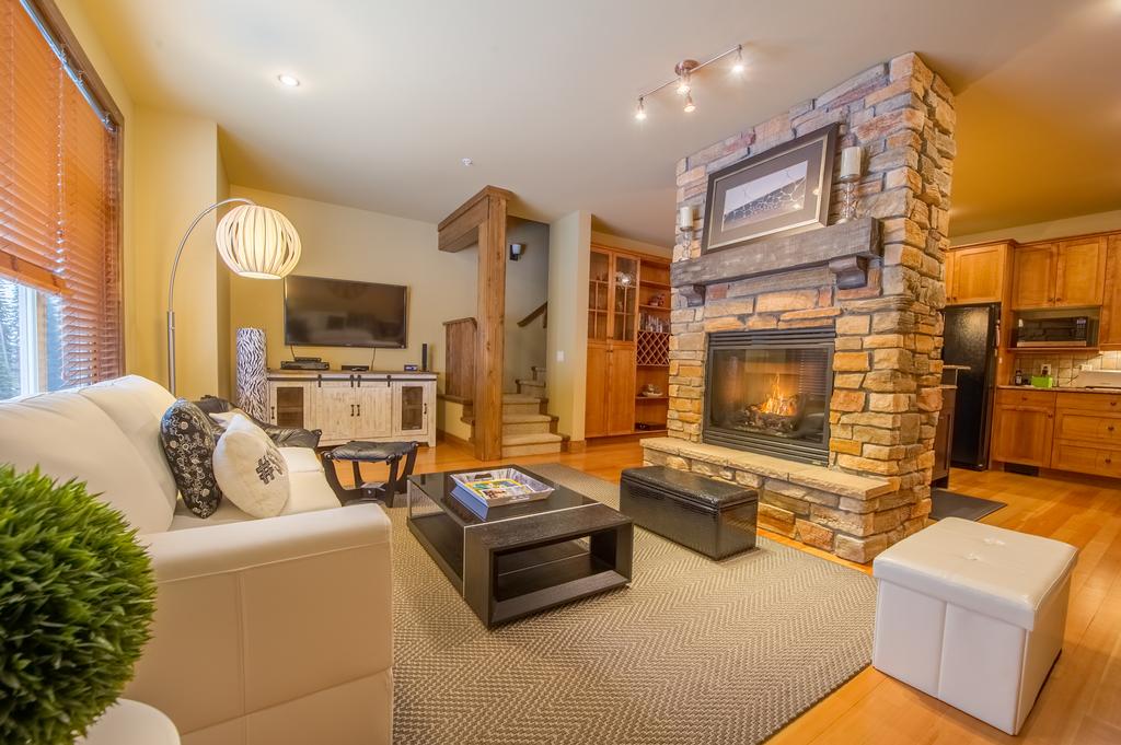 A cozy living room with a stone fireplace and warm lighting in a luxury vacation rental at Big White Ski Resort, managed by Luxury Mountain Vacation Rentals.
