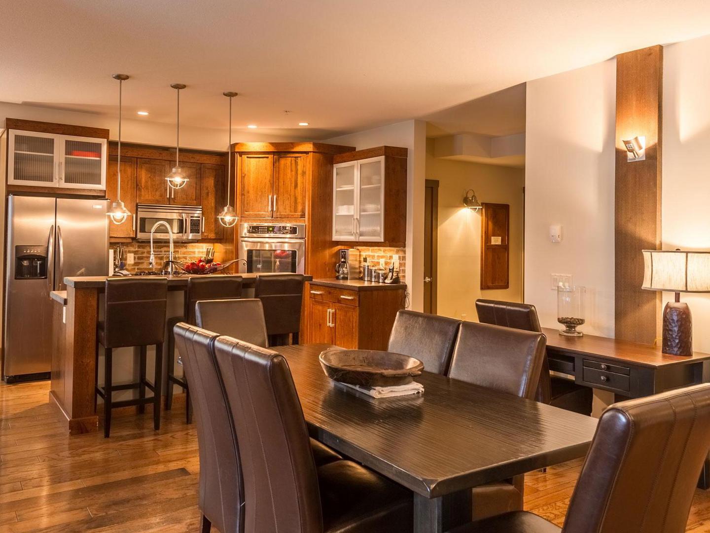 Timbers 304's open concept dining room and gourmet kitchen with a large dining table in a luxury vacation rental condo managed by Luxury Mountain Vacation Rentals at Big White Ski Resort.