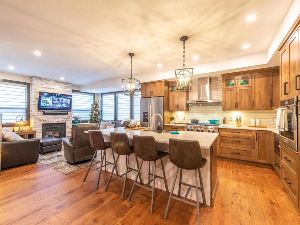 An open concept, gourmet kitchen with a large ba countertop with stools beside it in a luxury suite at Luxury Mountain Vacation Rentals at Big White Ski Resort.