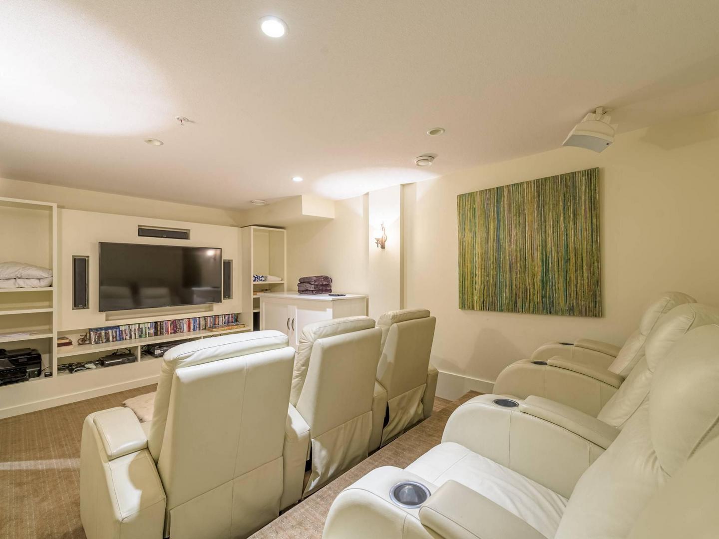 The private home theatre with white leather chairs and a large TV in the Edge 7.