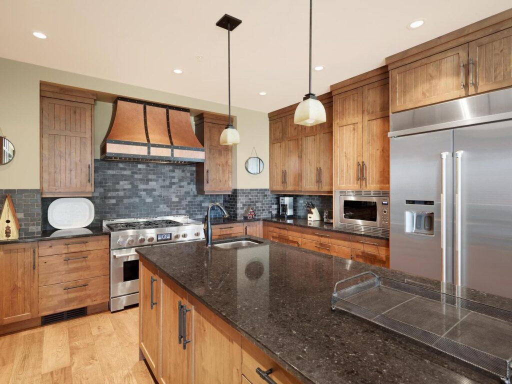 The large gourmet luxury kitchen at White Caviar Chalet with dark granite countertops, copper accents and hardwood floors.