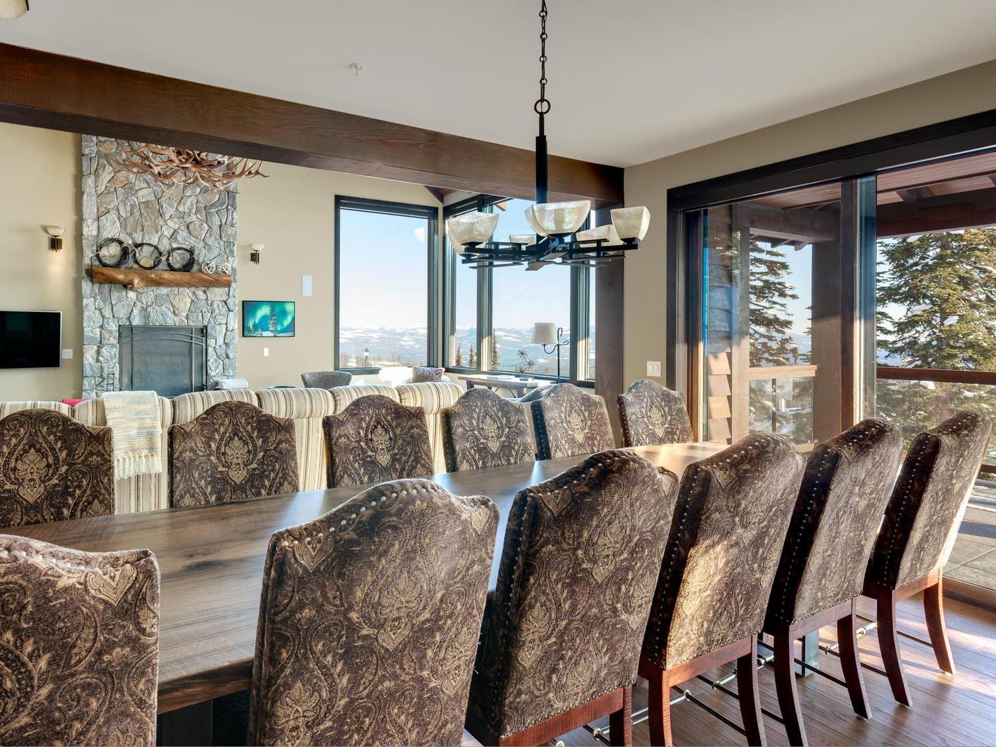 The luxury dining room with a large 12+ dining room table, plenty of natural light from large windows, and luxury furnishings in White Caviar at Big White Ski Resort.