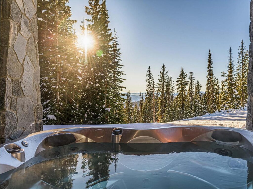 A beautiful forest view from the Snow Peaks Lodge hot tub on a sunny day at Big White Ski Resort.