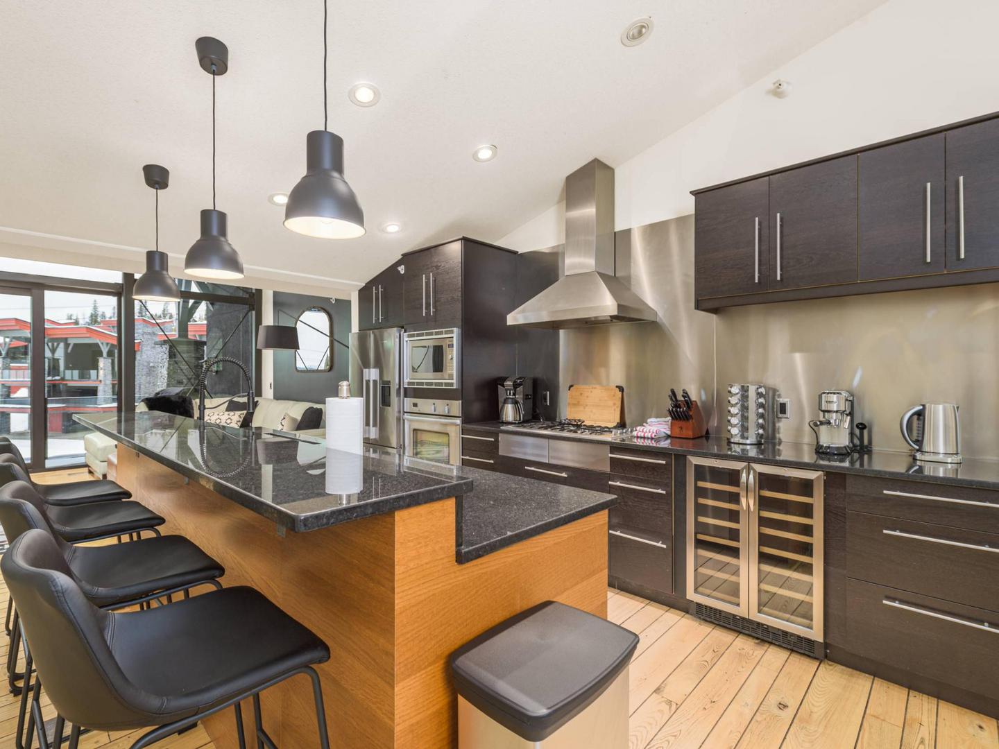 A luxury gourmet kitchen with dark countertops and cupboards and wooden accents in the Edge 3 luxury vacation rental.