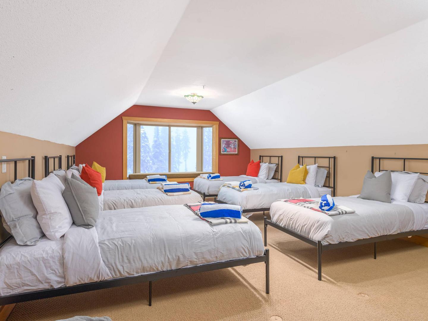 One of the bedrooms, with 6 single beds and bright natural light, perfect for comfortable accommodation for larger groups, in Raven's Wing at Big White Ski Resort. 
