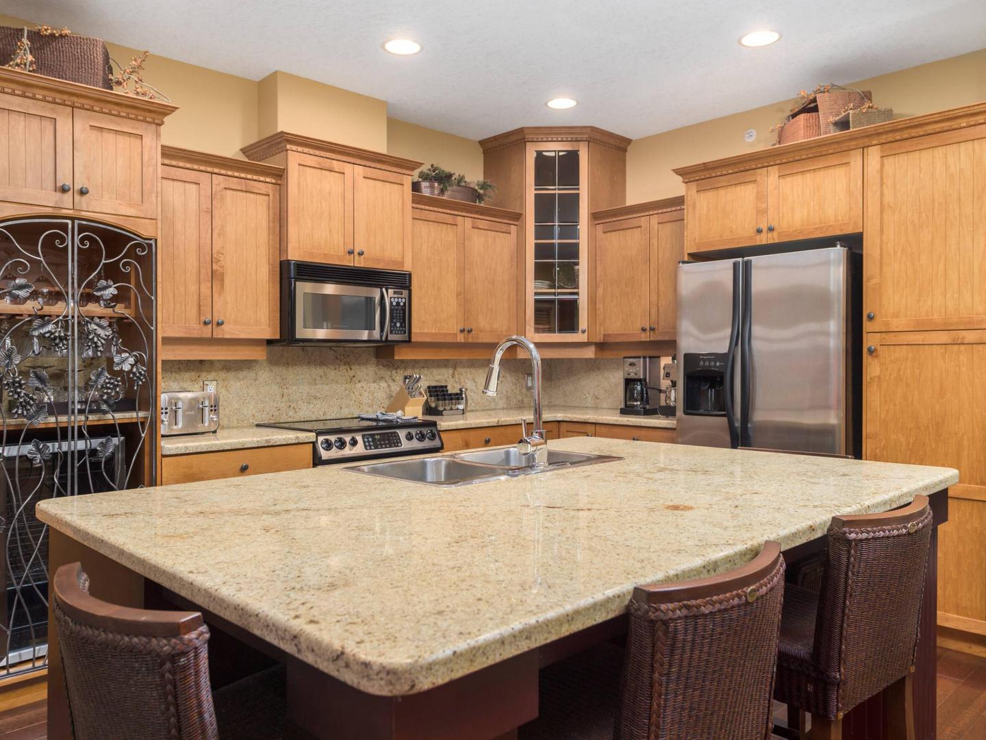 The large, marble-topped kitchen island in the traditional chalet-styled kitchen in Aspens #6 luxury vacation rental at Big White Ski Resort.