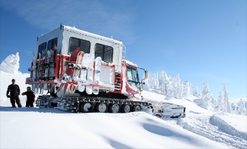 One of K3's cats, a large red painted machine covered in snow, used for cat skiing, an exclusive experience through Luxury Mountain Vacation Rentals at bigwhite.