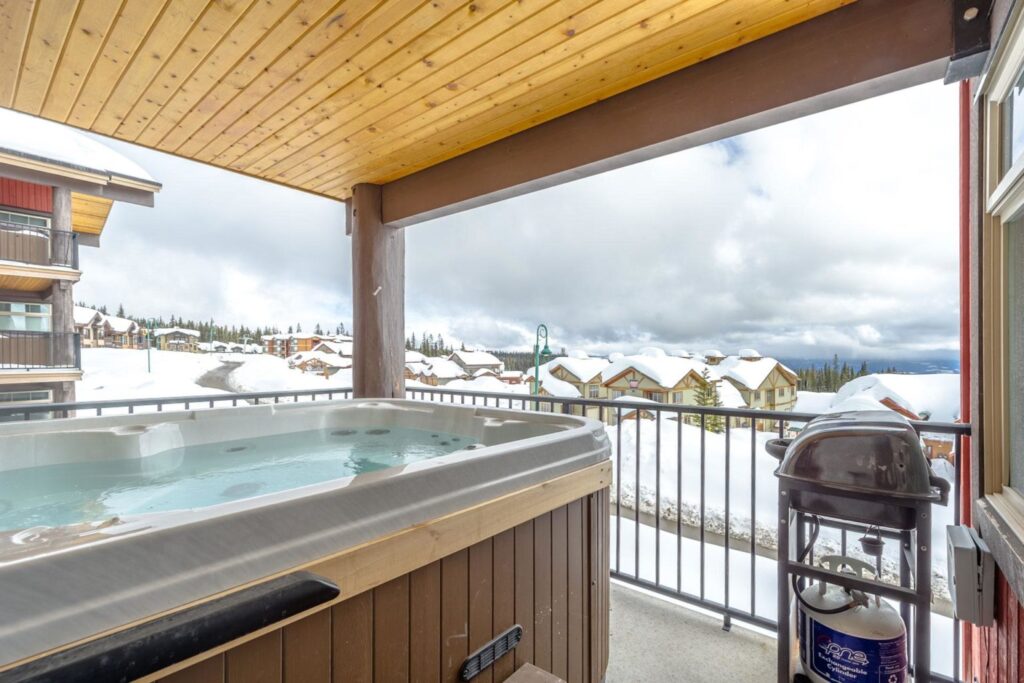 Pet-friendly Raven Unit 304's private deck with a private cozy hot tub and a personal barbecue with views of Big White Ski Resort.