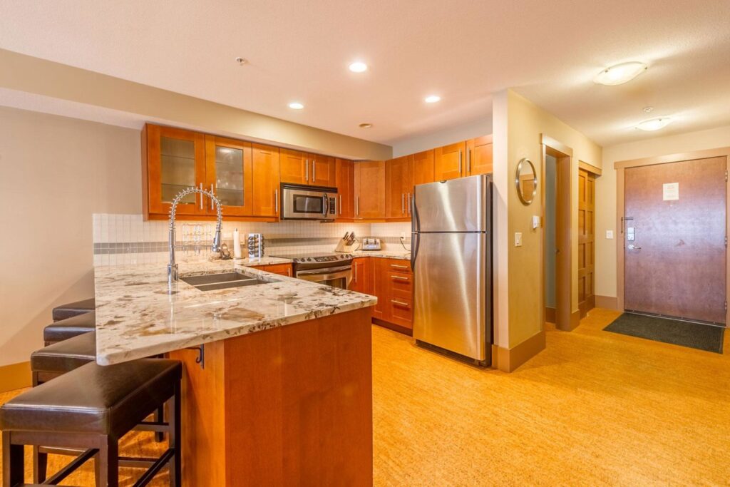 Pet-friendly Raven Unit 304's gourmet kitchen, which is fully-equipped with stainless steel appliances, marble countertops, wooden cabinets and floors.