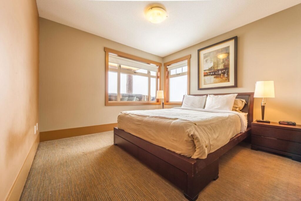 Pet-friendly Raven Unit 307's comfortable and relaxing bedroom, with bright light from windows, a comfortable bed and carpeted floors.