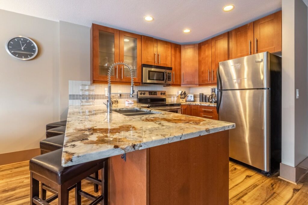Pet-friendly Raven Unit 308's luxury, fully-equipped gourmet kitchen with chestnut cabinets, stainless steel appliances, marble countertops and wooden floors.