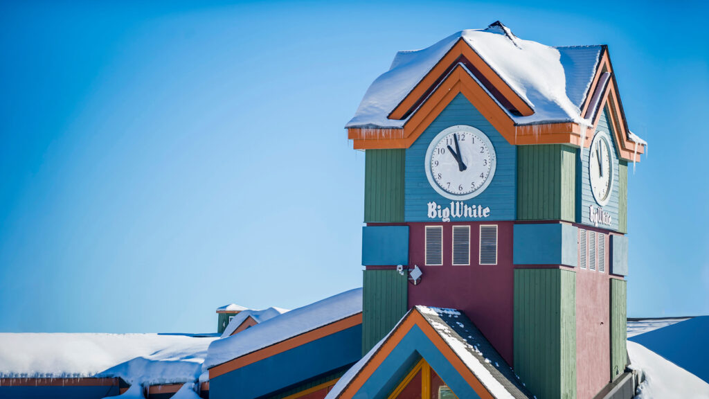 A large clock tower painted in bright colours with the words Big White on it, located at the Village Centre at Big White Ski Resort