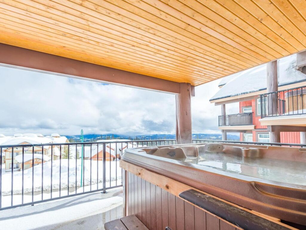 A luxury private hot tub in the Raven complex building, overlooking a snowy landscape at Big White Ski Resort, in a luxury rental condo owned by Luxury Mountain Vacation Rentals.