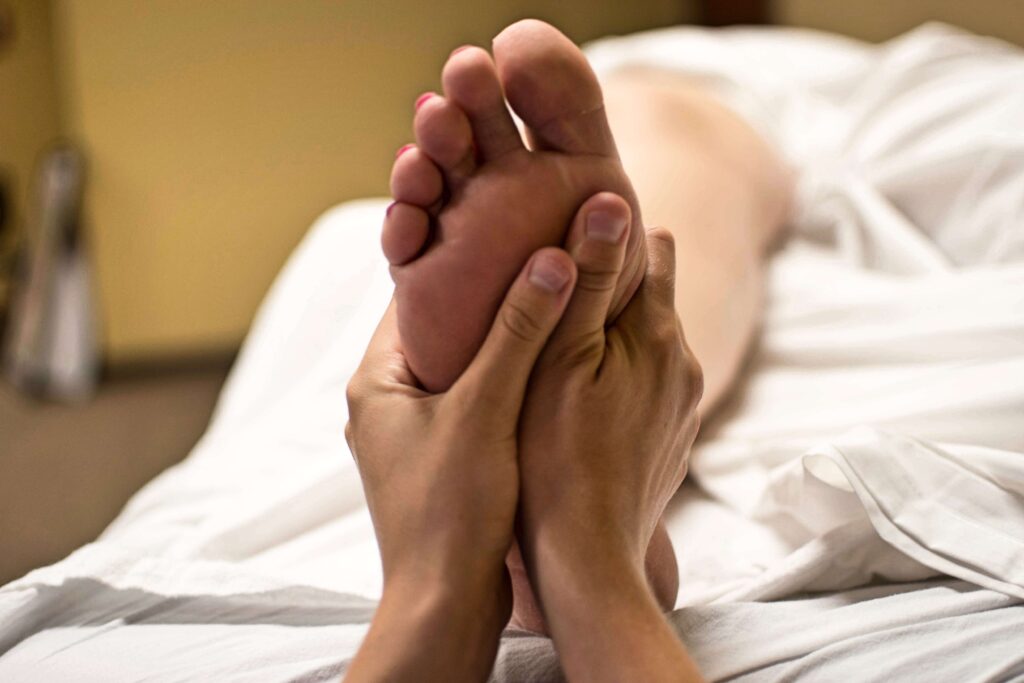 A registered massage therapist does location massage therapy on a patient's foot to relieve stress and heal pain in their body.
