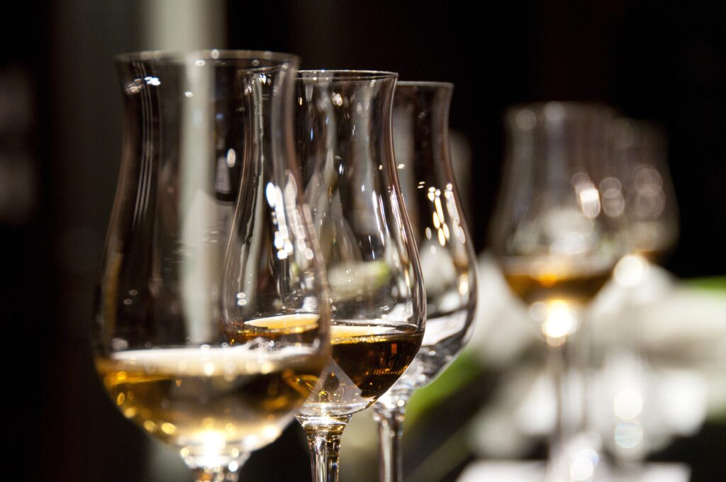 A set of curved wine glasses sit arranged in a line on a bar with a blurred background, set up for an expert sommelier private tasting with LMVR.