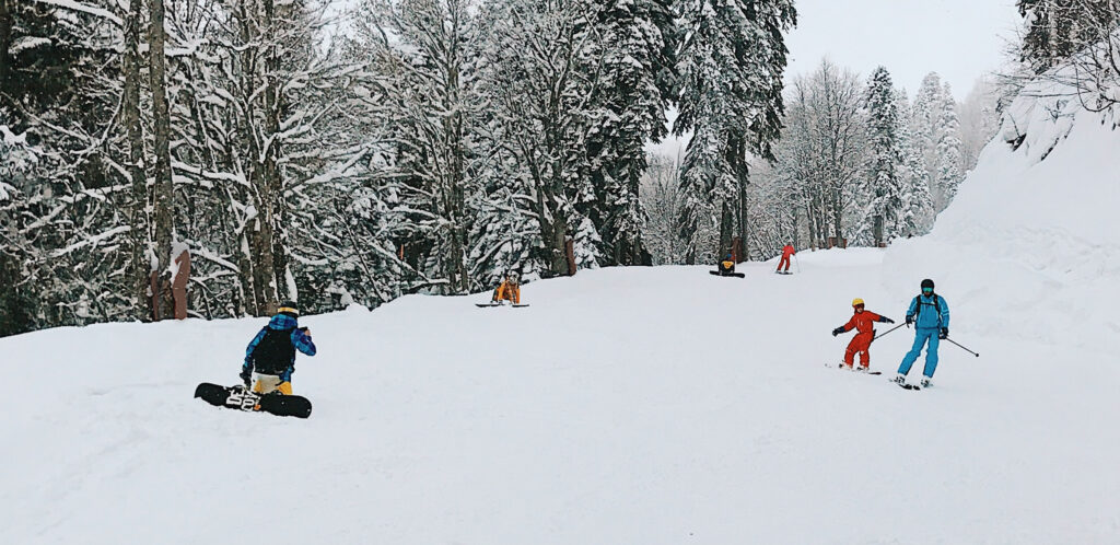 A group of people ski and snowboard down a white, snow covered slope at Big White Ski Resort.