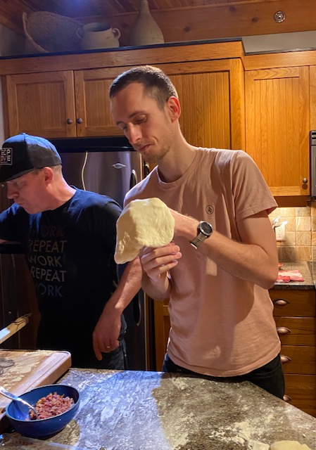 One of the Luxury Mountain Vacation Rentals staff tosses pizza dough in the air with Sean in the background while they make pizzas at Big White Ski Resort.