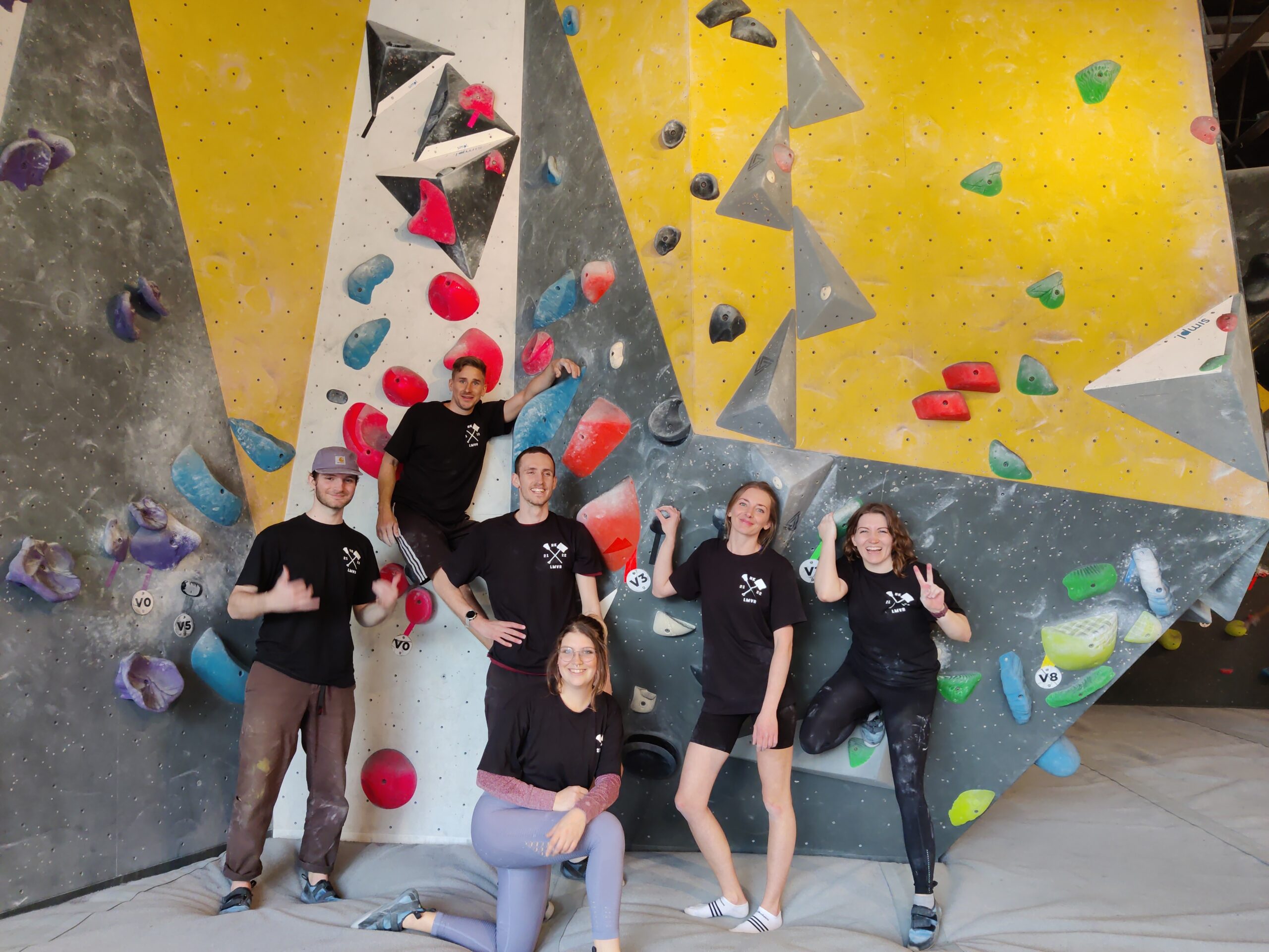 The staff of Luxury Mountain Vacation Rentals stand and pose in front of a rock climbing wall for a fun staff party at Big White Ski Resort.