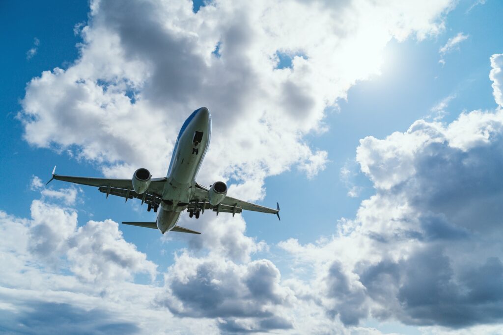 A large passenger plane travels through the sky with blue skies and clouds above heading to Big White Ski Resort.