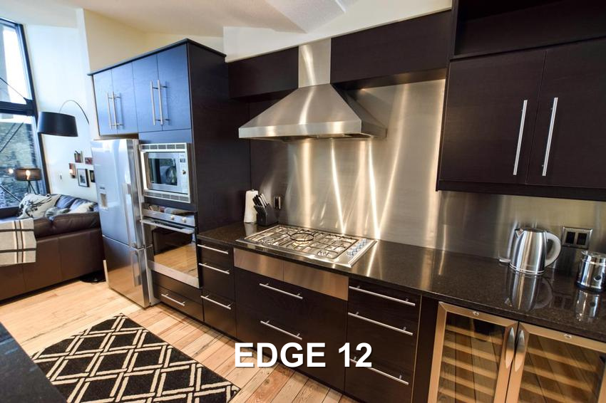 Edge 12's luxury gourmet kitchen with dark cabinets and stainless steel appliances, managed by Luxury Mountain Vacation Rentals at Big White Ski Resort.
