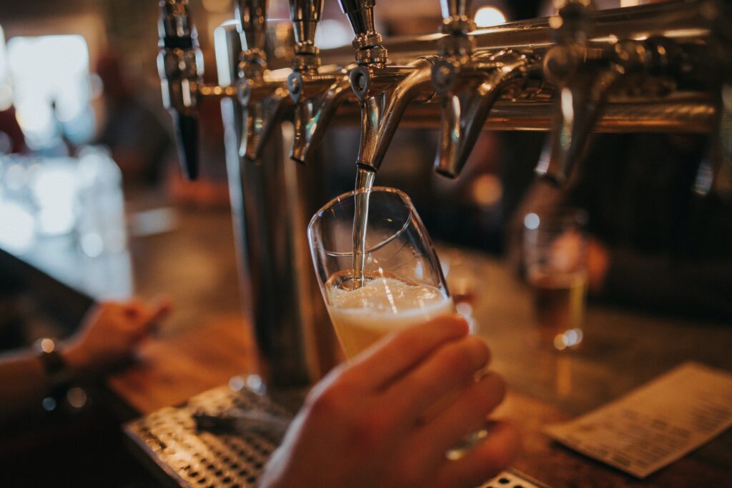 A bartender pours a pint of cold beer from tap at a pub.