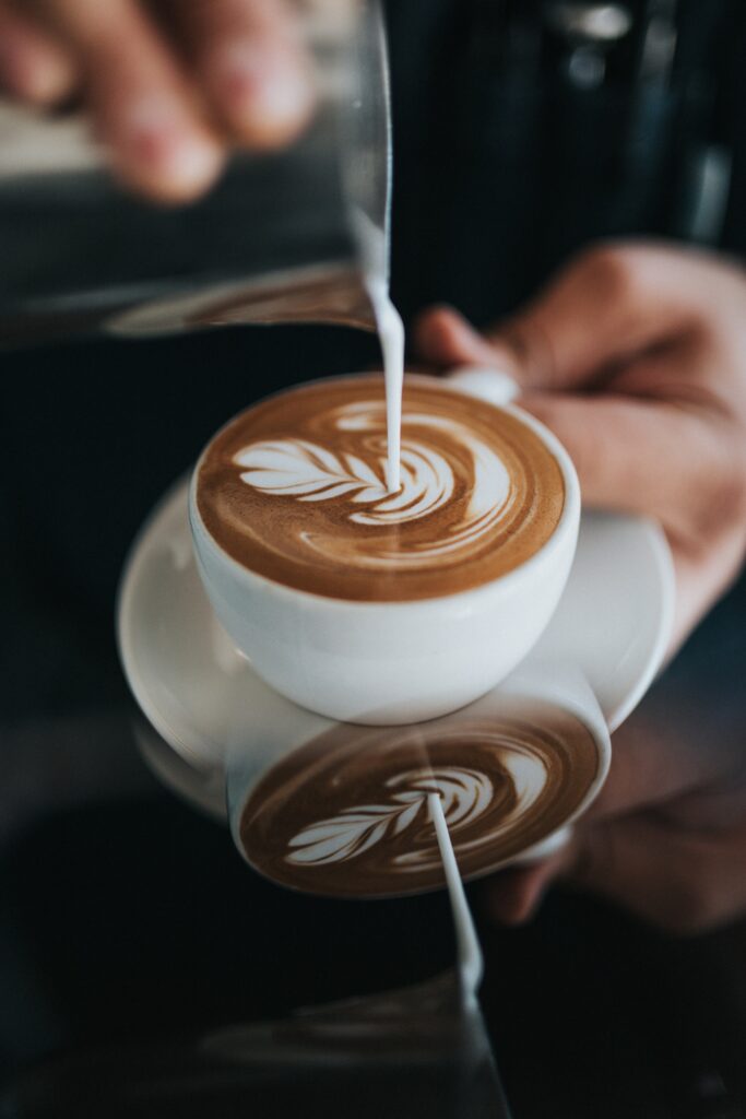 A barista pours steamed milk to make latte into a white mug, making a latte art leaf pattern. Grab a fresh cup of coffee from some of the mountain's best joints, including Globe Café, Moose Lounge and Clocktower cafe. 